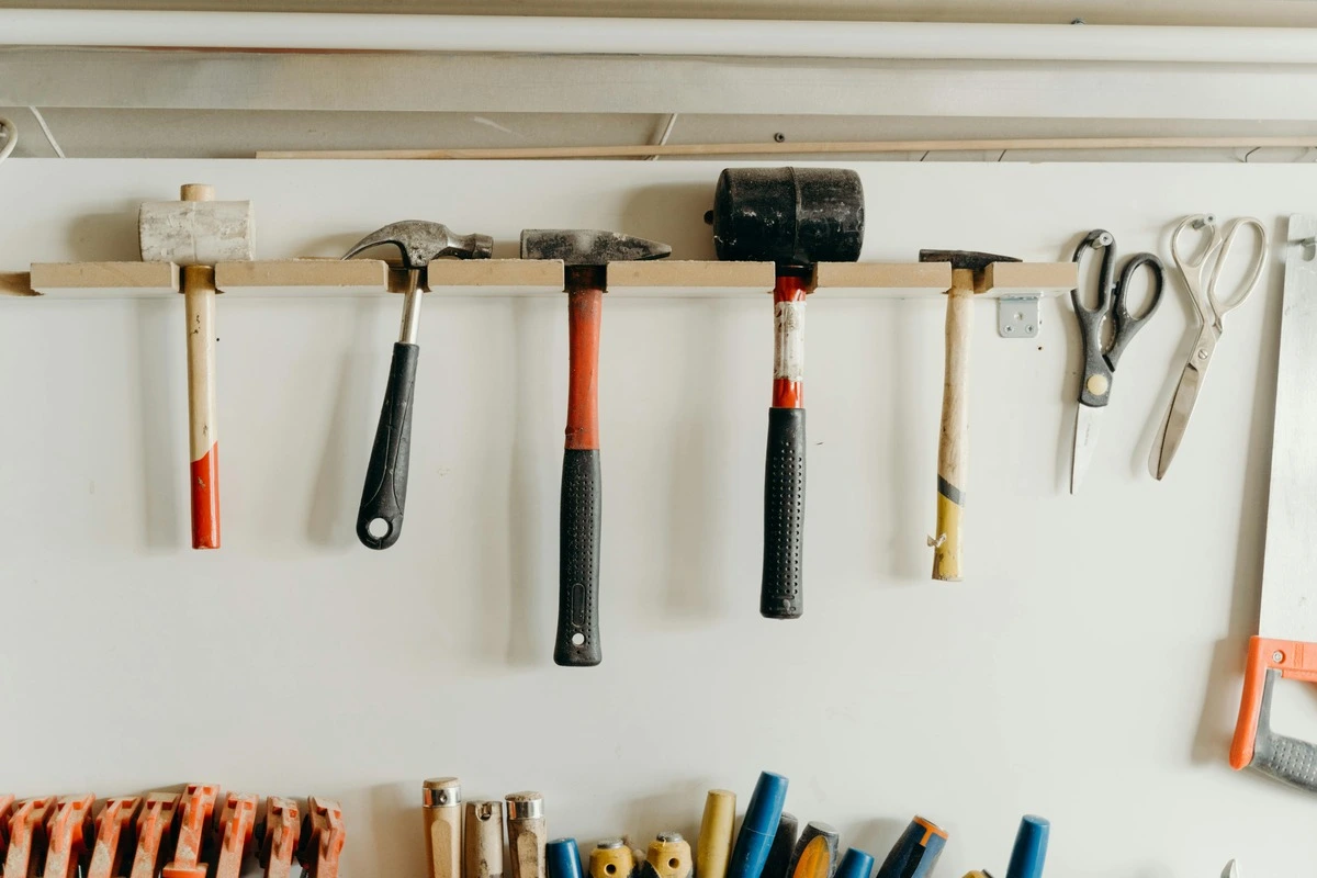 Different types of hammers hanging on a tool shelf