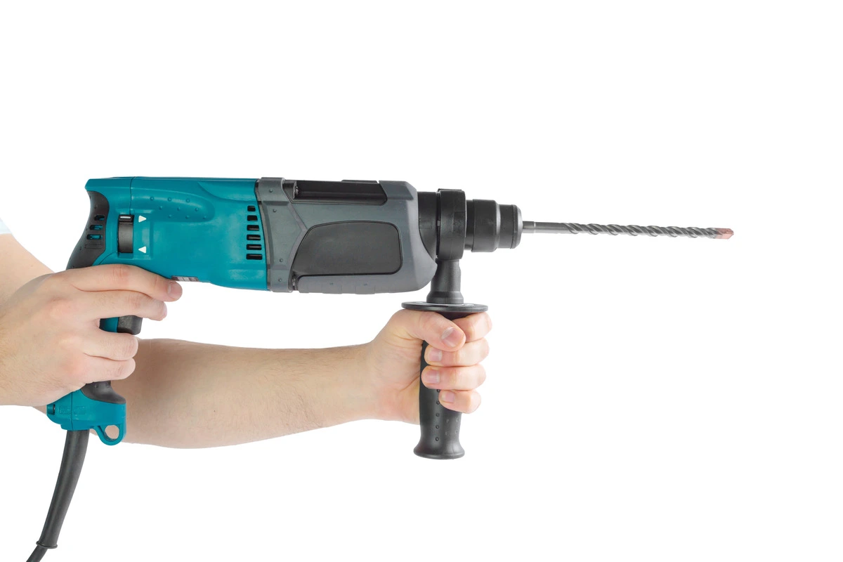 A person holding a hammer drill in the hand on white background
